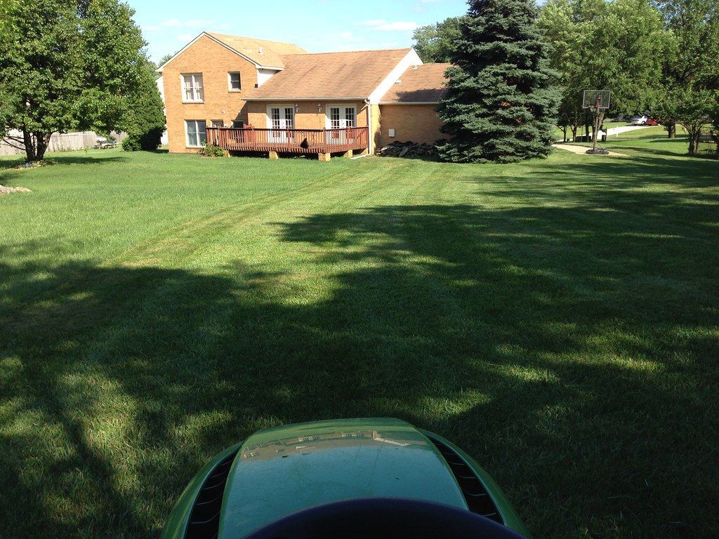 Riding mower crossing a freshly striped front lawn